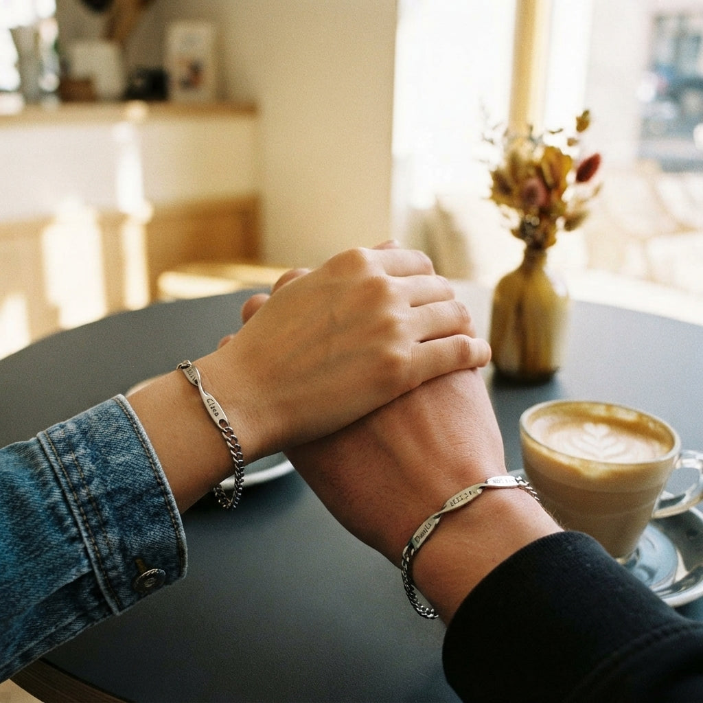 A couple wearing matching personalized Mobius strip bracelets while holding hands in a modern cafe.
